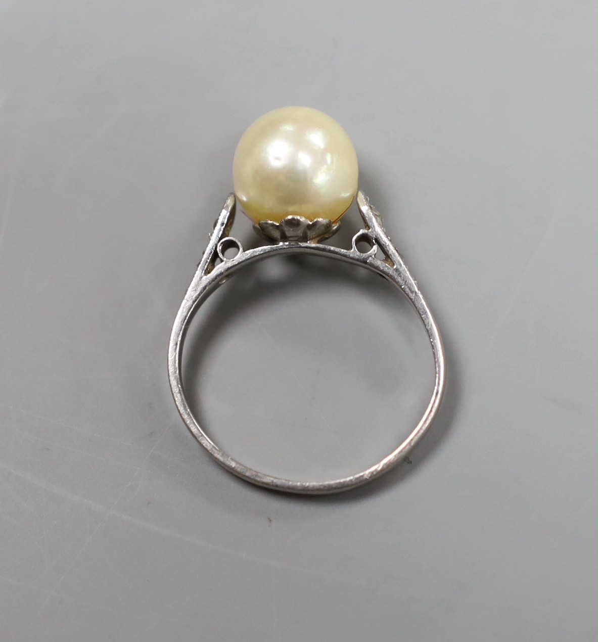 A solitaire cultured pearl set ring, with diamond chip set shoulders, size K